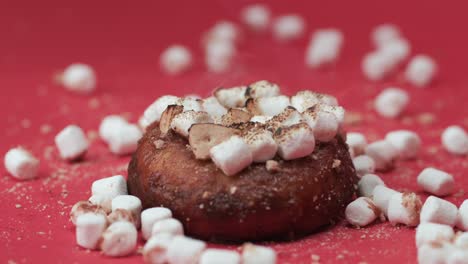 close-up roasting marshmallows on a chocolate donut in studio, red background