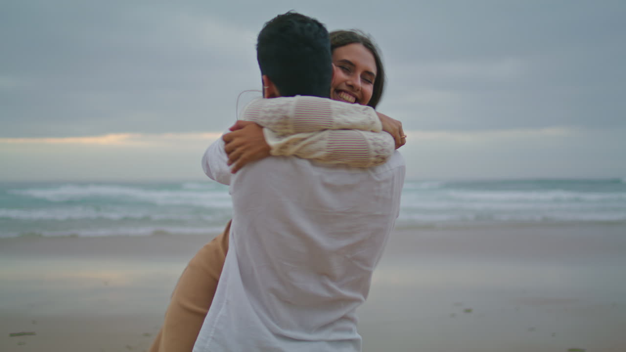 una pareja comprometida abrazándose en la playa del océanos al atardecer.