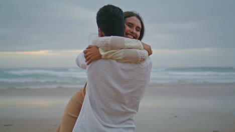 una pareja comprometida abrazándose en la playa del océanos al atardecer.