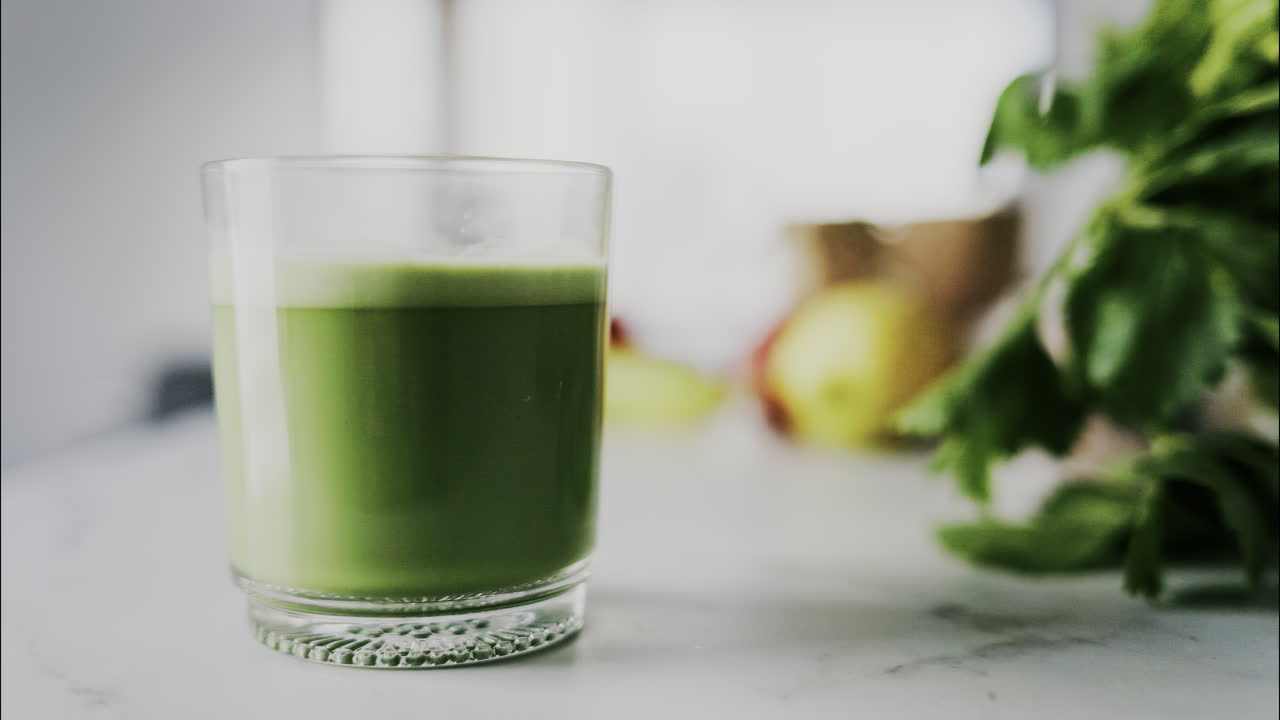 Primo piano di un bicchiere di succo verde su un tavolo da cucina bianco
