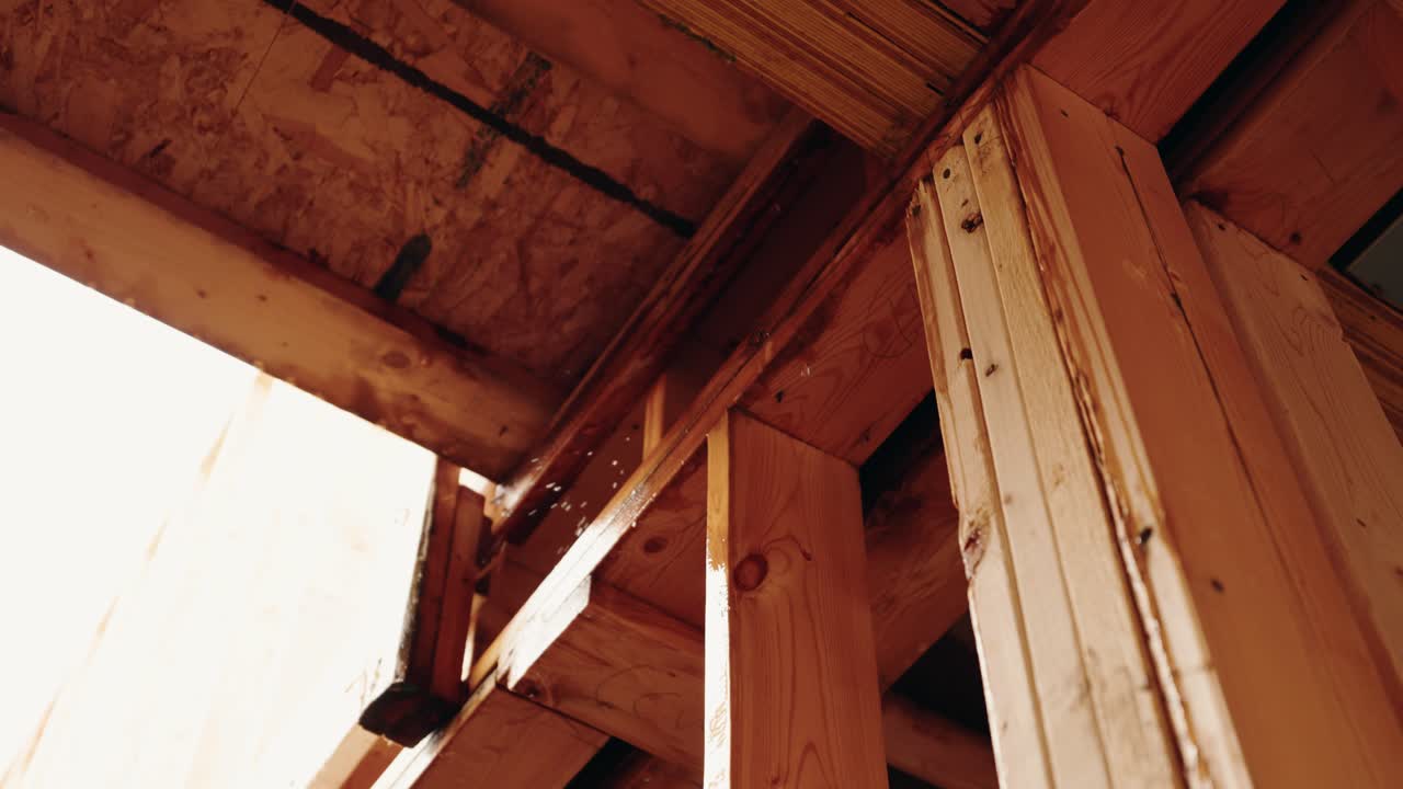 Slow motion reveals rain falling through wet wooden boards of home under build