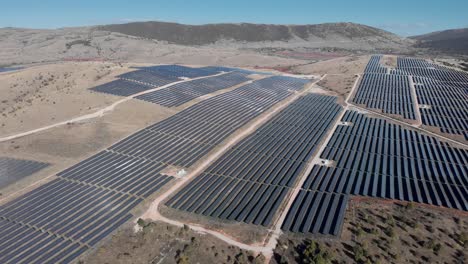 descendiendo drone sobre el parque de energía solar fotovoltaica fila paneles colinas panorámica