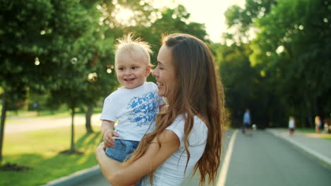 Mother-holding-toddler-on-hands.-Woman-and-boy-looking-at-soap-bubbles-on-street