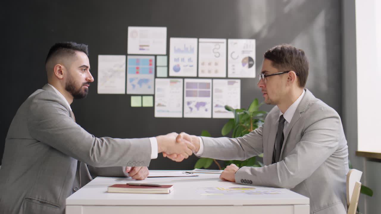 Two Businessmen Talking and Shaking Hands at Office Meeting