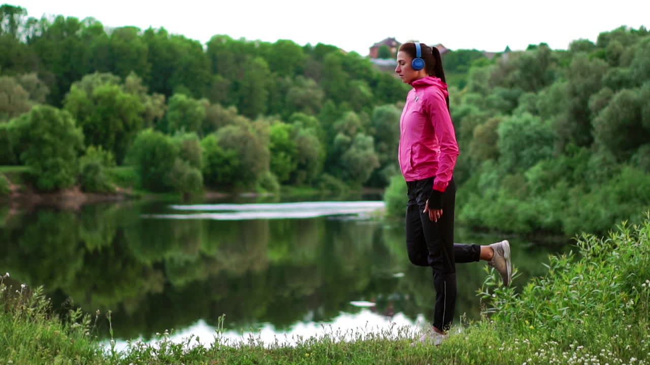 소녀는 훈련 전에 아침 일찍 따뜻해지고  ⁇ 빛에서 달리기를 준비합니다.