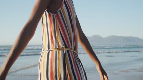 african american mother walking with daughter on sunny beach