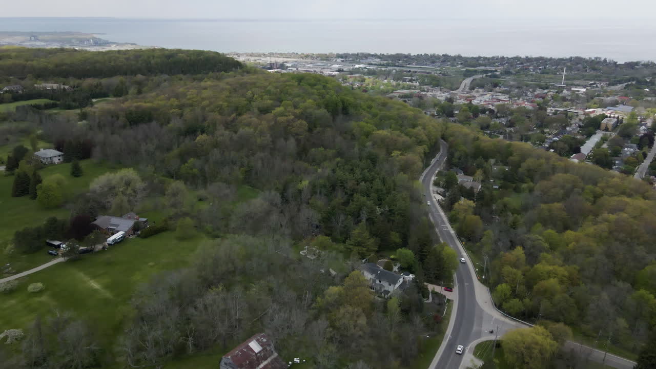 sobrevuelo aéreo carretera rural en el suburbio con coches de conducción y hermoso lago ontario en el fondo, canadá