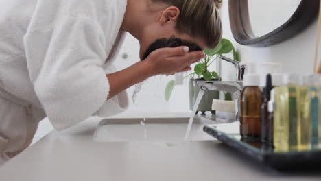 Mujer-Birracial-Lavando-Mascarilla-De-Belleza-En-El-Baño,-Cámara-Lenta