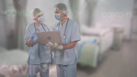 animation of words covid-19 floating over two doctors wearing face masks using a laptop