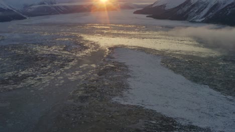 Hielo-Cubrió-El-Agua-Del-Océano-En-La-Bahía-Durante-La-Aparición-Del-Amanecer-Sobre-Las-Montañas,-Antena