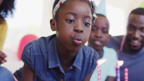 african american girl blowing candles on the cake at home