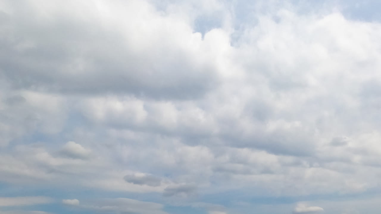 White clouds spreading along the horizon. Cloudscape in the sky on rainy daytime. Low angle view. Timelapse.