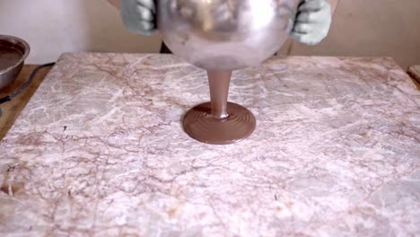 un confitero anónimo vertiendo chocolate en un tablero de mármol