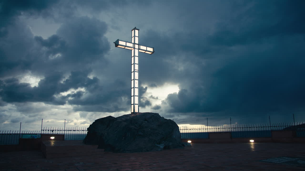 Dramatický obraz zářícího křesťanského kříže vystupujícího ze skály pod temnými bouřkovými mraky, symbolizující víru a sílu v nepřízni osudu