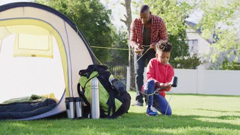 Happy-african-american-father-and-his-son-setting-up-tent-in-garden