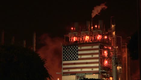 smoke rises from an oil refinery, illuminated at night