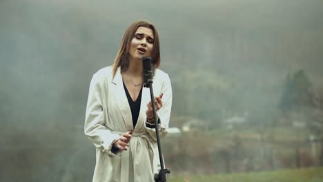 Young-artist-girl-surrounded-by-fire-and-smoke-singing-on-microphone