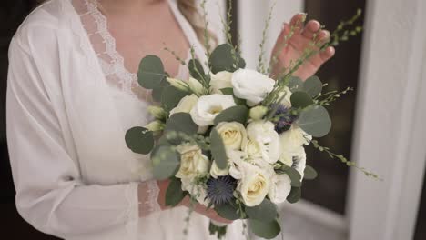 bride holding an elegant bouquet of white roses and eucalyptus leaves