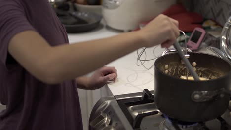 a young girl stirs a caramel mix heating up on the stove while baking millionaire shortbread cookies-4