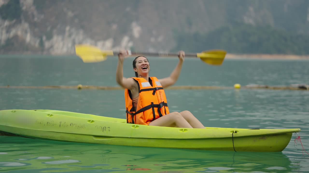 A woman joyfully kayaking on a lake