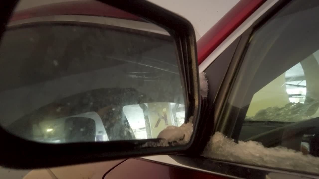 Push in shot of a red car mirror in the parking garage.
