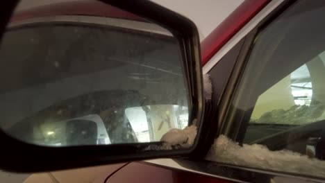 push in shot of a red car mirror in the parking garage.