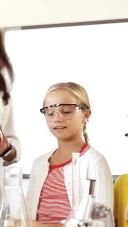 maestro asistiendo a los niños de la escuela en hacer experimentos en el aula