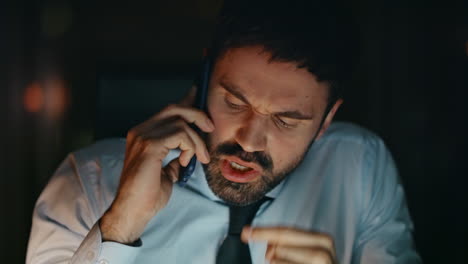 closeup furious businessman calling sitting office late evening. manager yelling