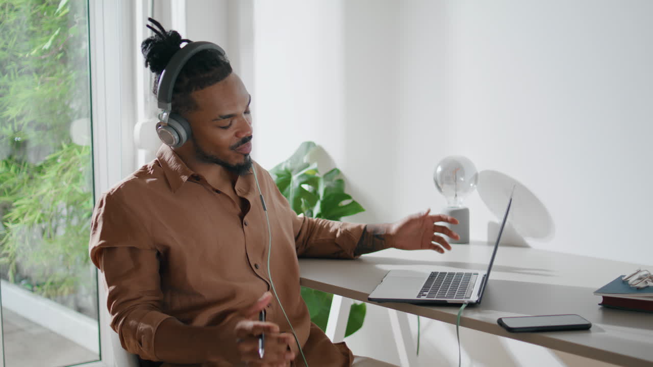 Positive student wearing headphones at home closeup. Freelancer talking greeting
