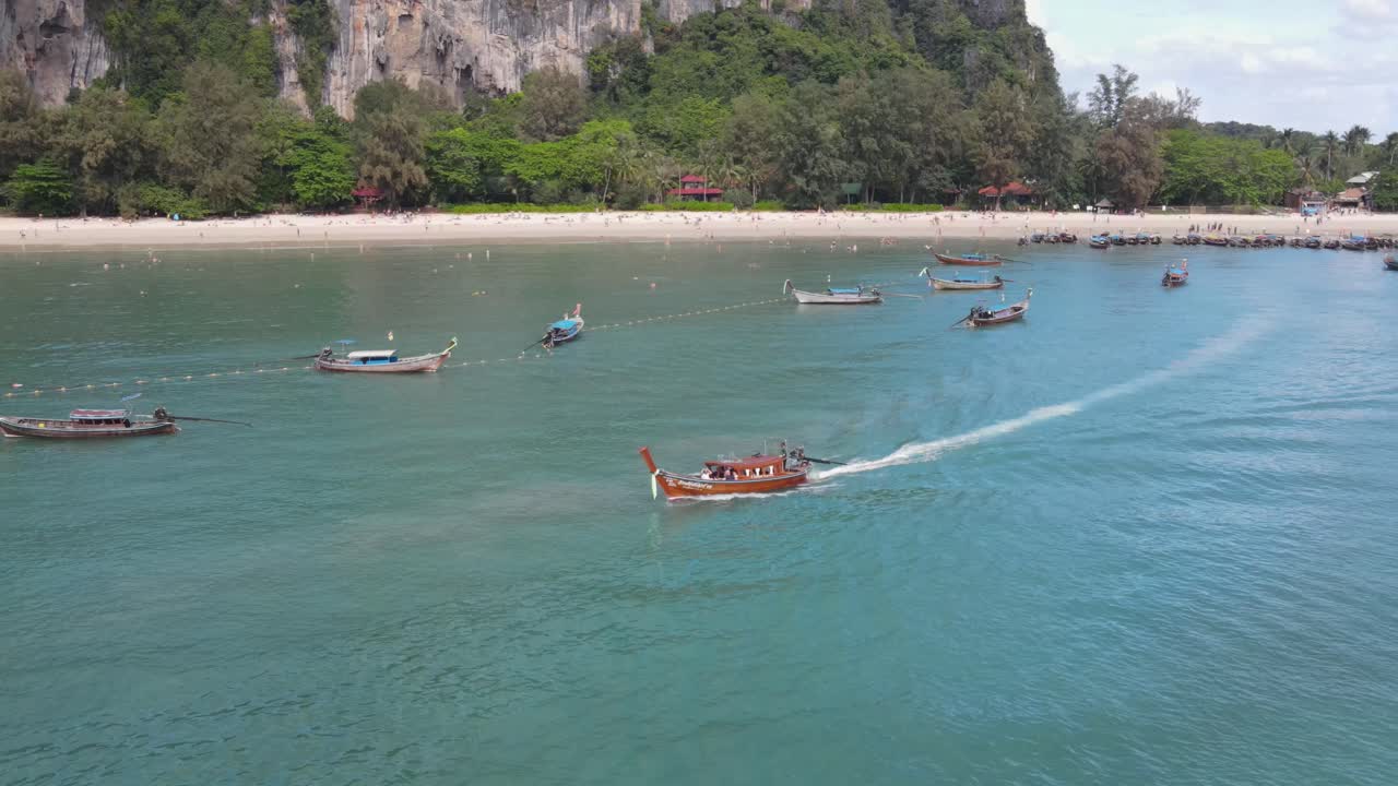 라이 레의 배경에 석회암 절벽이 드러나는 판과 함께 해변을 떠나는 롱테일 보트의 항공 전망