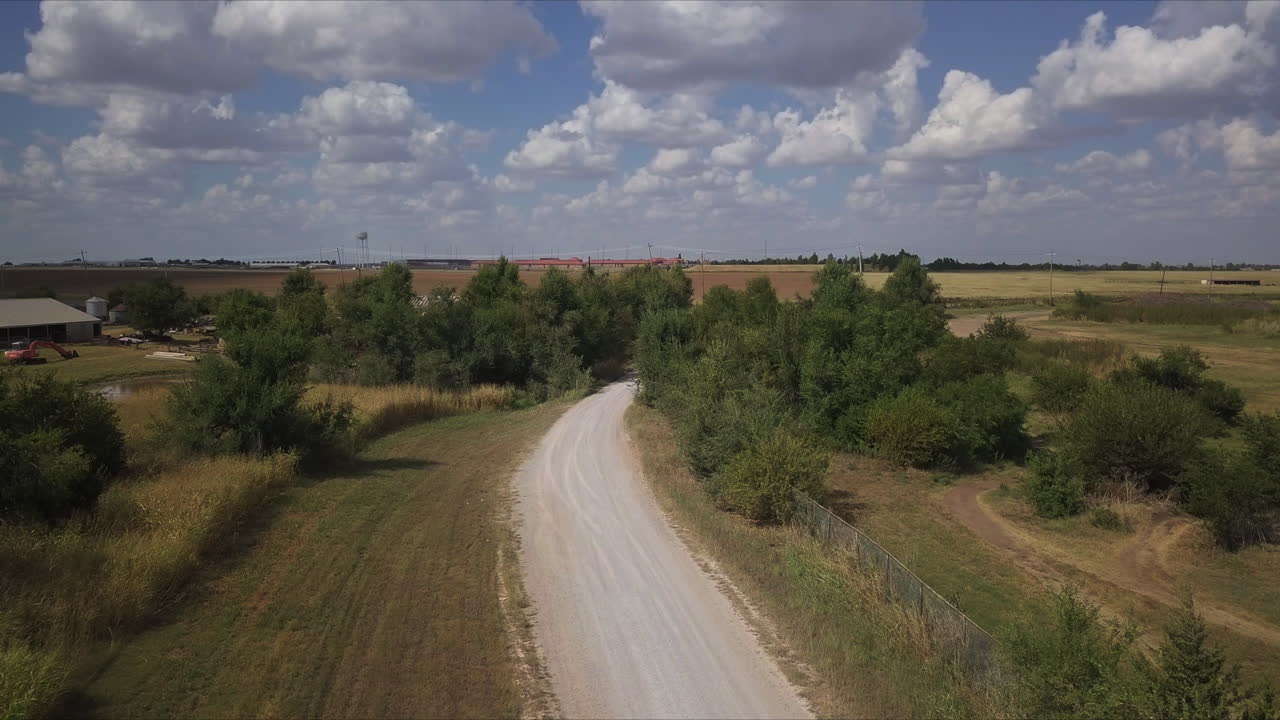 camino polvoriento en el campo con cielo nublado y azul, coches vistos pasar