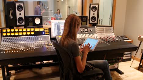 Female-audio-engineer-using-sound-mixer-using-digital-tablet