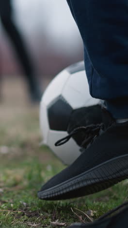 blurred view of a football being passed between two people on a grassy field, with one person trapping the ball under his foot