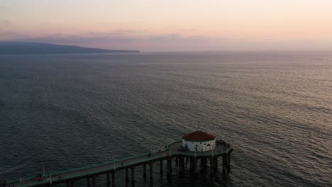 Fly-Over-Manhattan-Beach-Pier-With-Roundhouse-Aquarium-Against-Gloomy-Sky-In-California,-USA