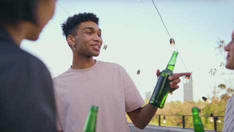 carefree people toasting drinks at summer rooftop closeup. friends clinking beer