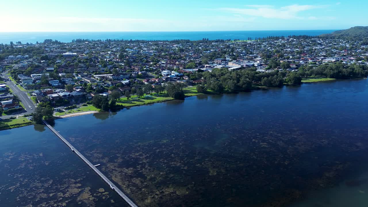 Drone aerial landscape of Long Jetty rural suburban town neighbourhood with housing on streets and boardwalk pier wharf in Tuggerah Lake lagoon river system Central Coast Australia urban living