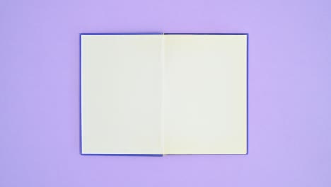 blue hardcover vintage book appear on purple theme and open. stop motion flat lay