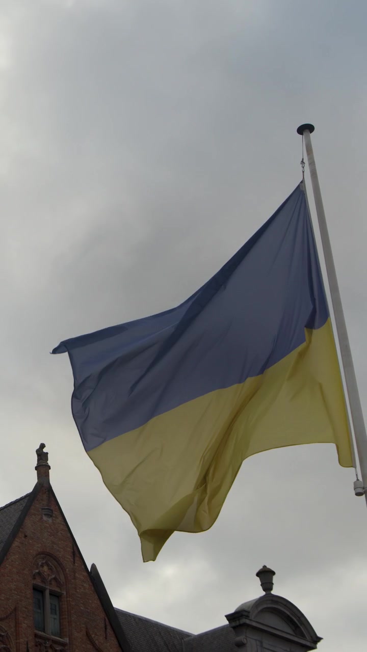 Bandiera ucraina sventola sull'asta contro un cielo nuvoloso, edifici medievali, telecamera statica, illuminazione nuvolosa