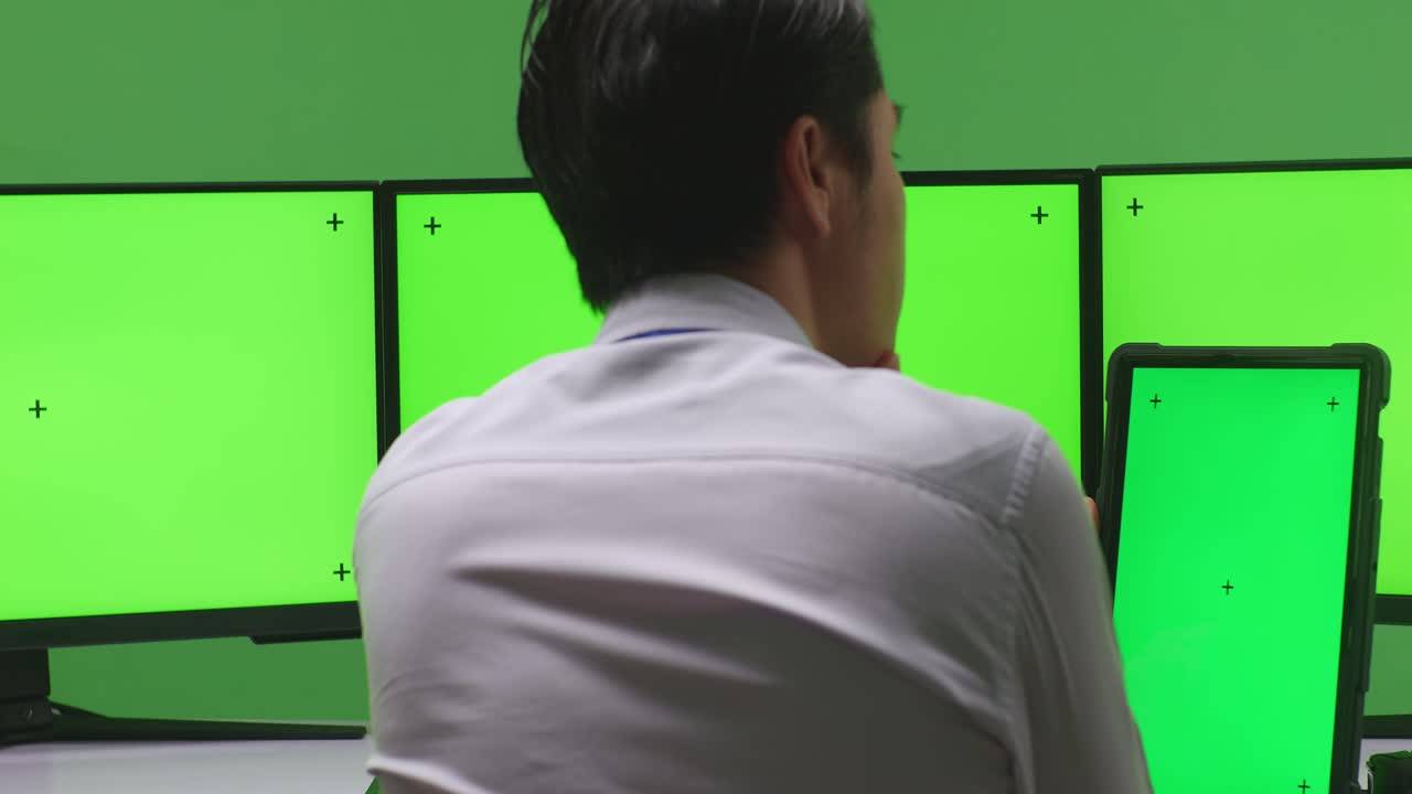 녹색 화면 모니터와 태블릿을 가진 제어 센터에서 일하는 사업가