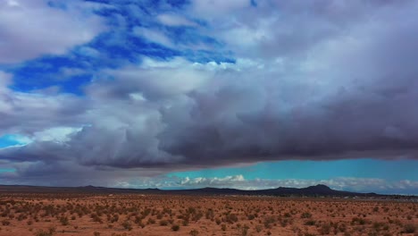 cuenca del desierto de mojave con las lejanas y escarpadas montañas en un día nublado con grandes cúmulos en el cielo - vista aérea deslizante