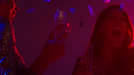 cerca de dos mujeres en un bar de club nocturno o discoteca bailando y bebiendo alcohol con confeti de papel 1