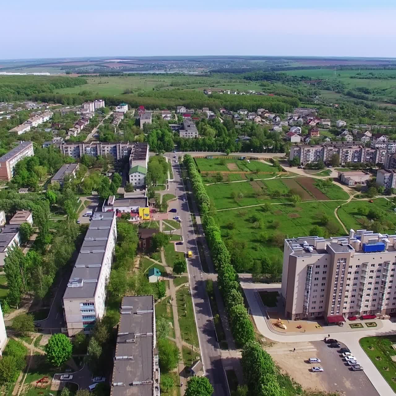 Provincial city panorama shot on sunny day in summer. Residential neighborhoods and green zones from aerial perspective