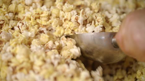worker mixing popcorn in popcorn machine with scoop. preparing food for movie