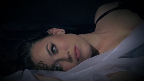 gorgeous woman is restless in bed, and turns to face to camera in a close-up