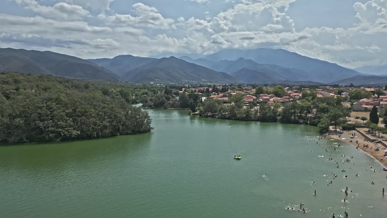 People enjoying sunny day at Lake Vinça, Eastern Pyrenees in background. Aerial