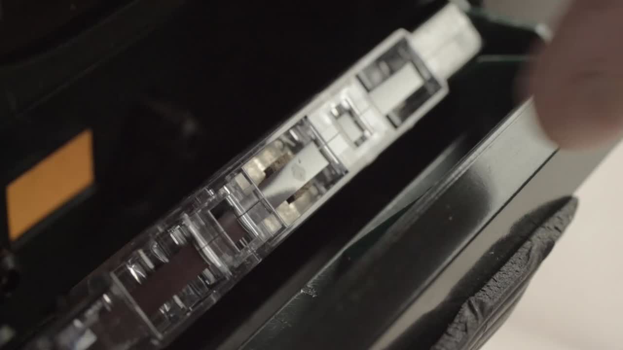 Hand inserting retro cassette tapes into radio cassette player macro