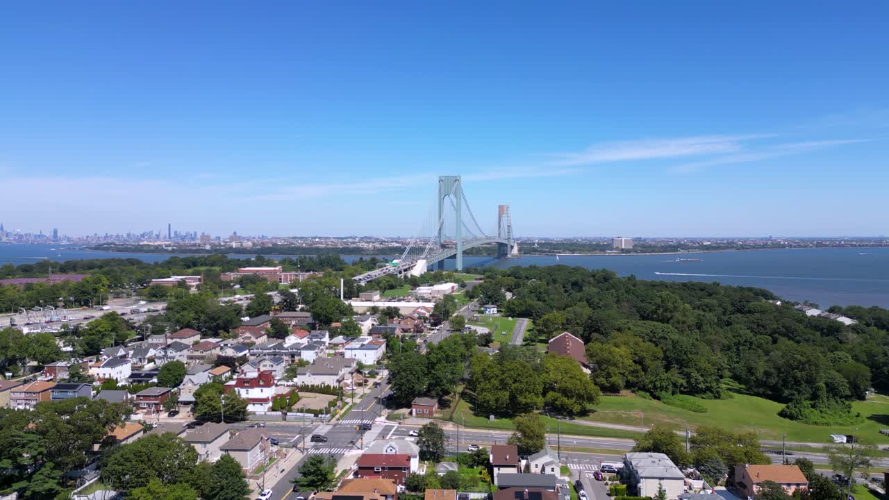 Stunning aerial view of Staten Island and the Verrazzano-Narrows Bridge with a clear skyline, waterfront, and residential neighborhoods under a bright blue sky