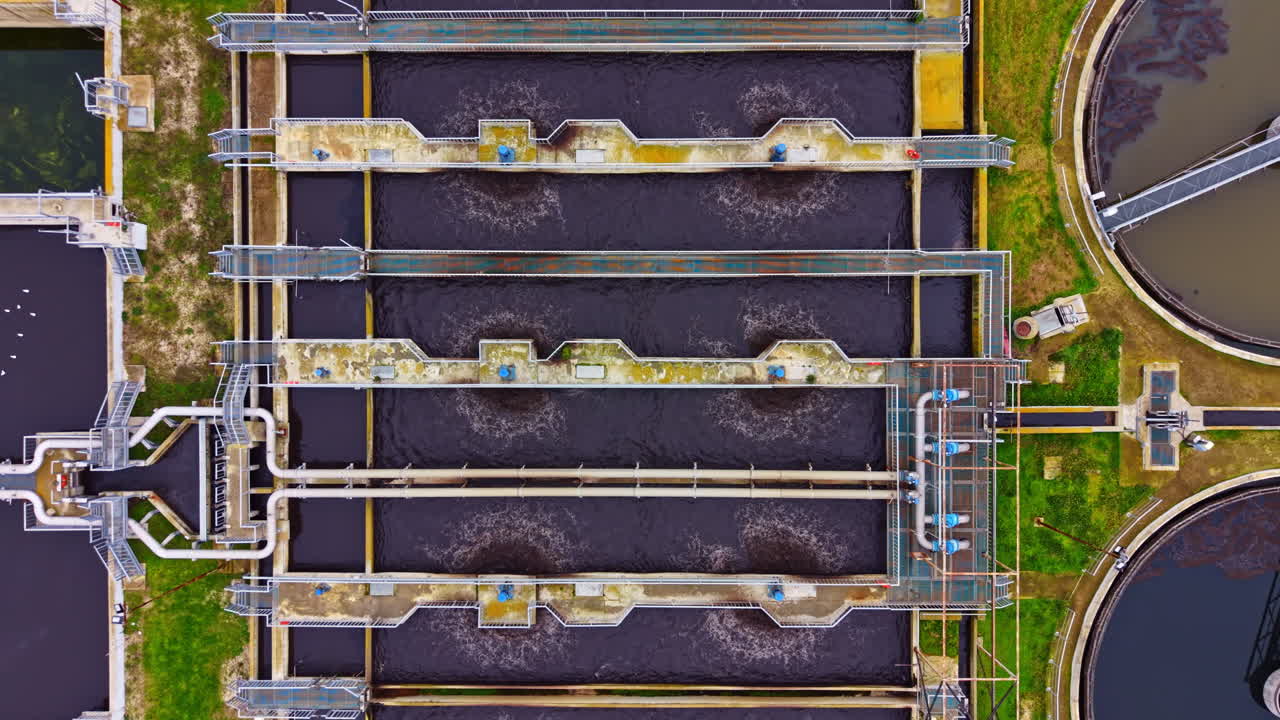 View of wastewater treatment plant with multiple tanks and processing equipment during daylight in an industrial area