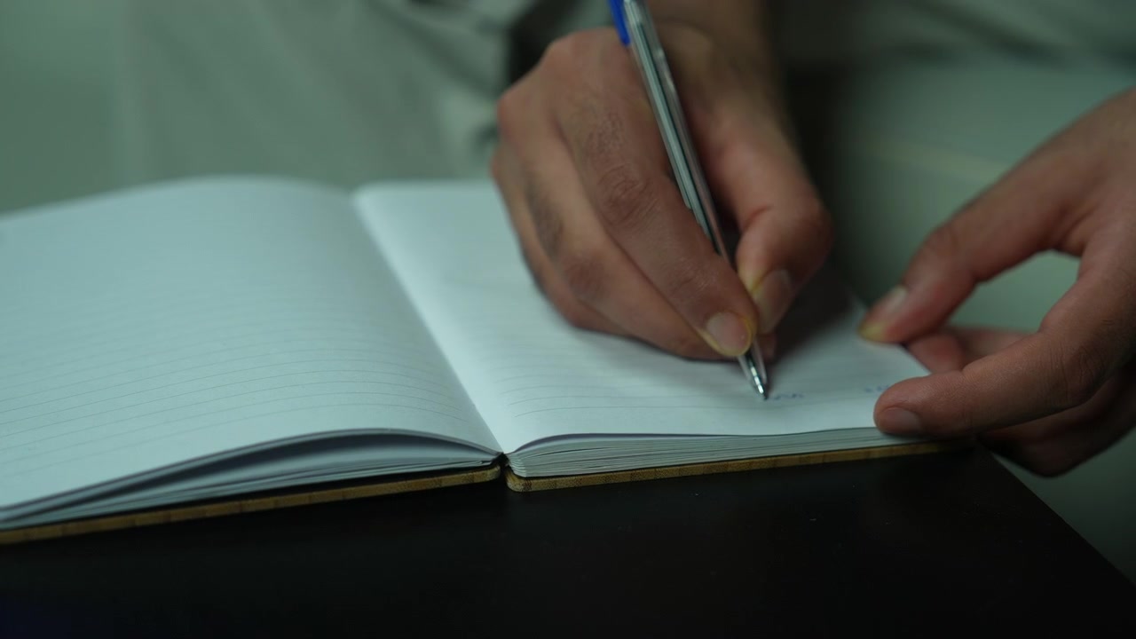 Hand holding and writing in pages of empty book on table, closeup
