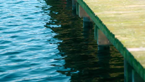 Ondas-Y-Resplandor-Solar-En-El-Agua-De-Las-Olas-Cerca-De-Un-Muelle